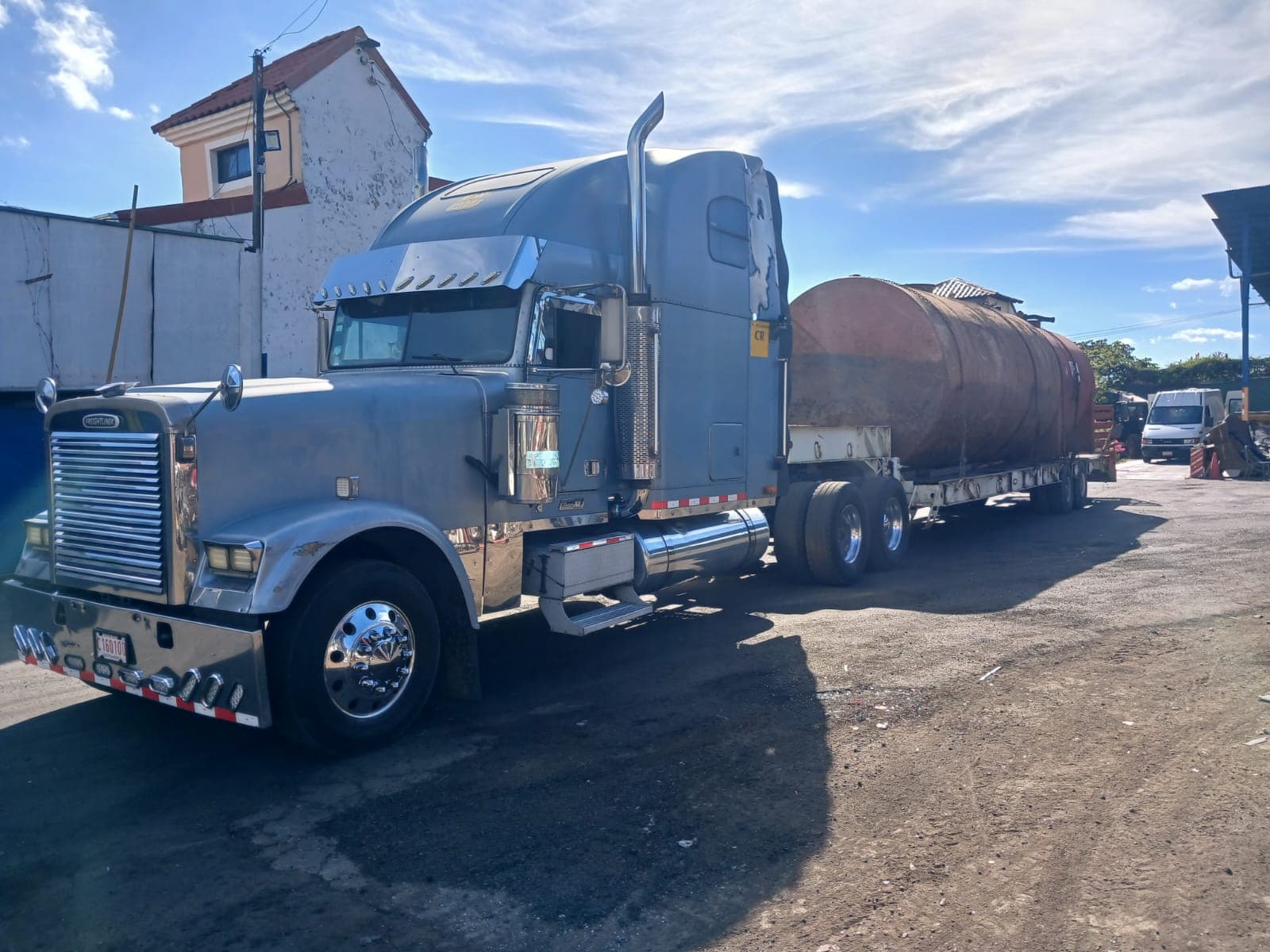Freightliner Classic XL plateado con un tanque en la plataforma