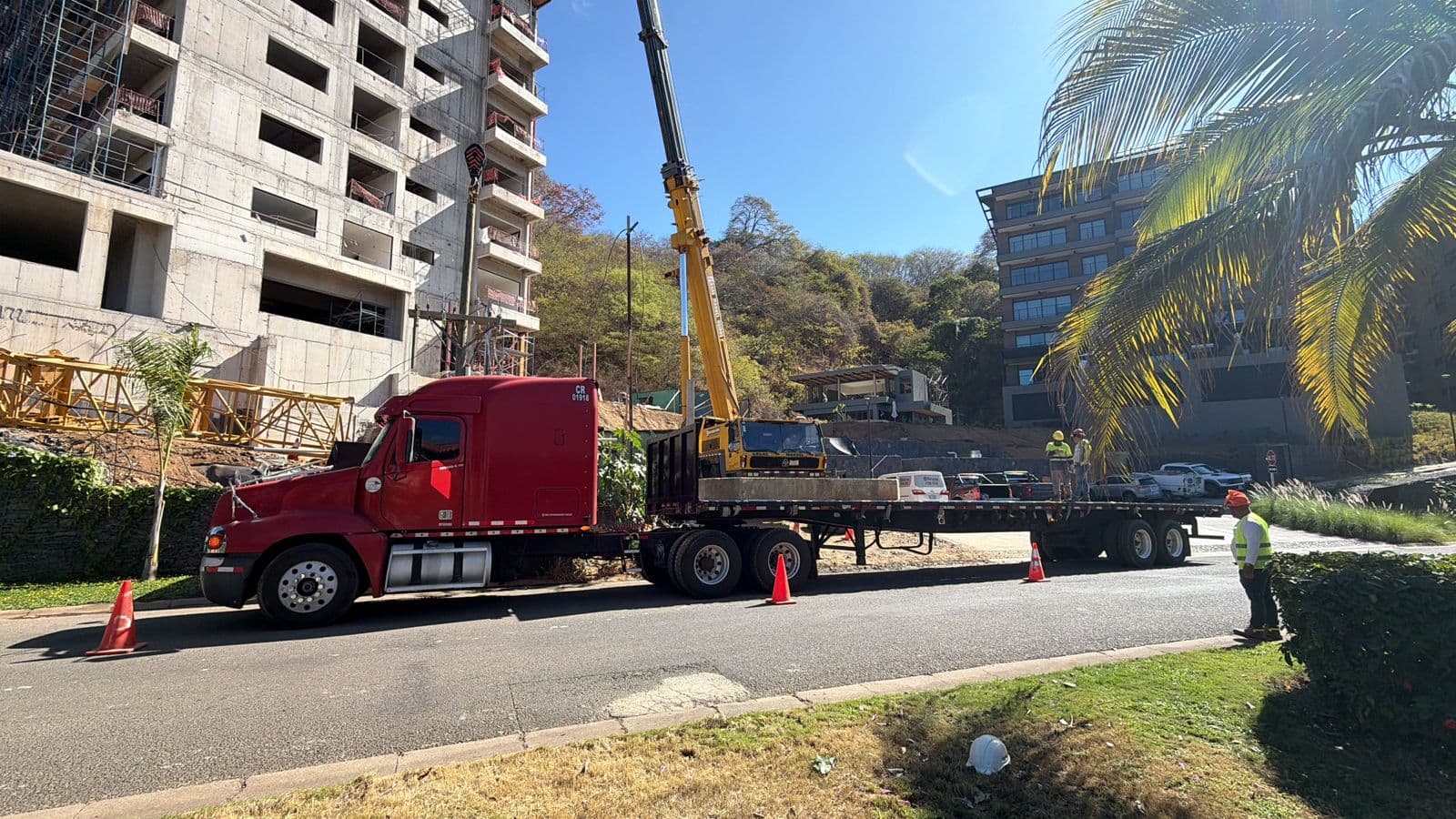 Cabezal rojo con secciones de grúa torre listas para descargar en una obra