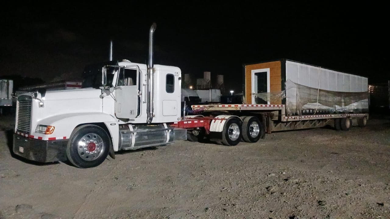 Cabezal blanco con un módulo tipo contenedor en la plataforma, de noche