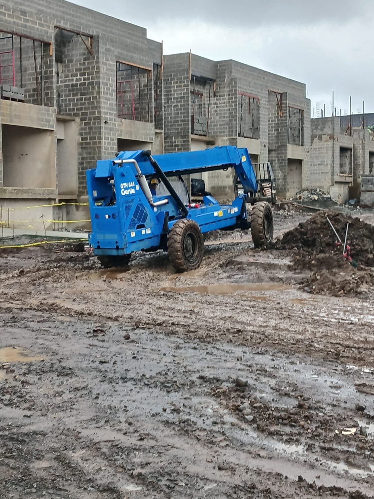 Telehandler Genie azul en el barro de una obra de casas