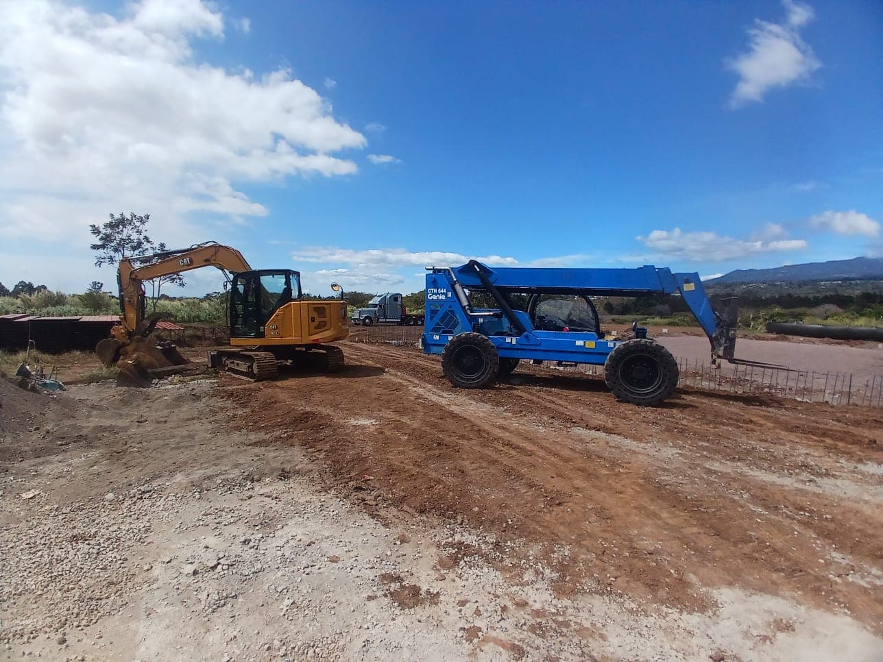 Telehandler Genie y excavadora CAT trabajando en un terreno