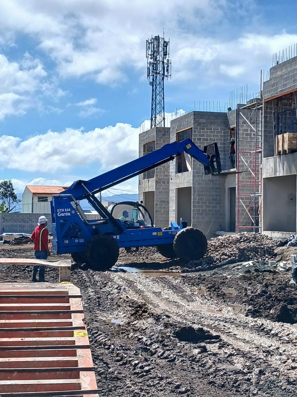 Telehandler Genie junto a una casa en construcción